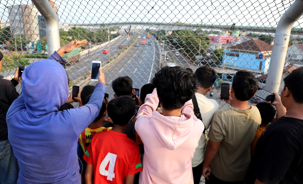 Anak-anak sedang menunggu bus yang membunyikan 'klakson telolet' dari atas jembatan penyebarangan.
Fenomena mendengarkan bunyi klakson kendaraan tolelet di kalangan ana-anak sudah menjadi hobi karena mereka dapat merekam dan mendokumentasikan bunyi ke dalam ponsel. | Foto: media Asuransi/Arief Wahyudi