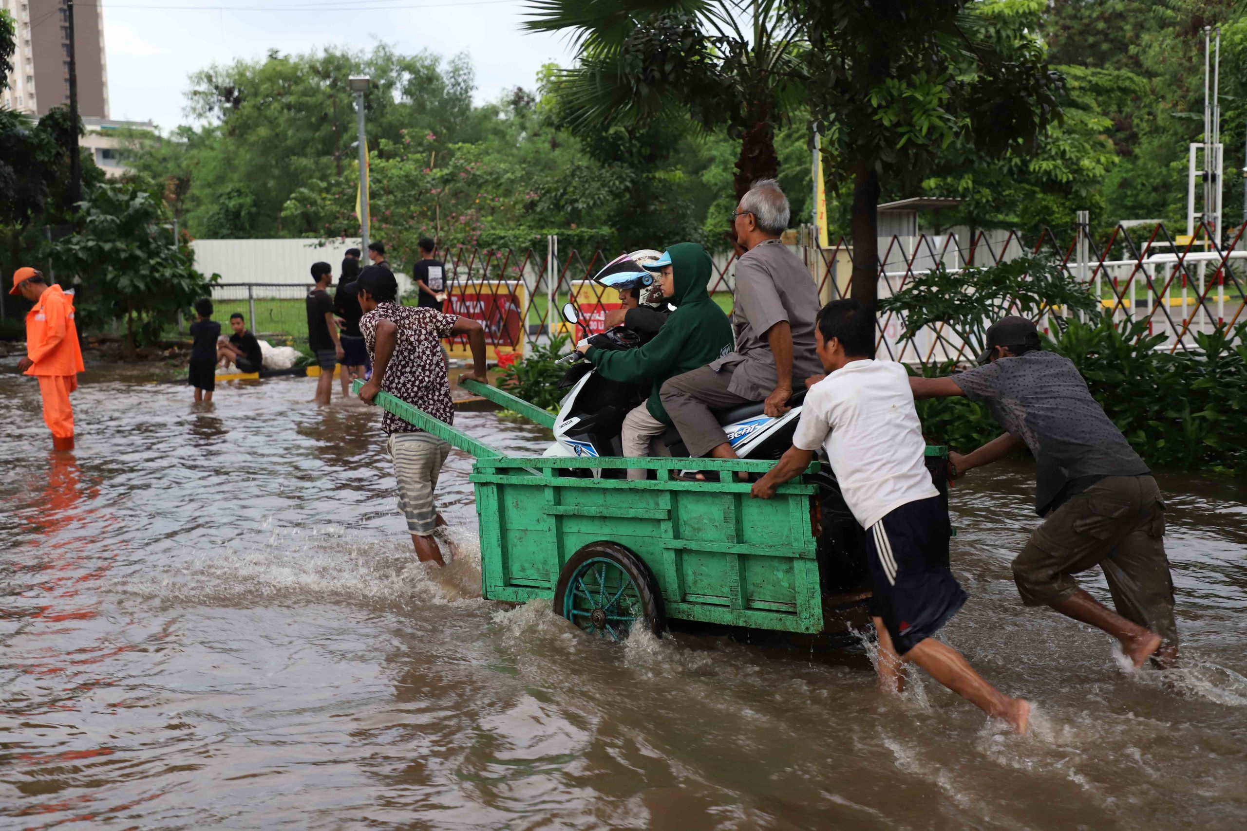 Warga pengguna sepeda motor yang terhadang banjir di Jalan Cileduk Raya, Sabtu, 6 Juli 2024), memanfaatkan jasa perahu gerobak untuk menyeberangi banjir. | Foto: Media Asuransi/Arief Wahyudi