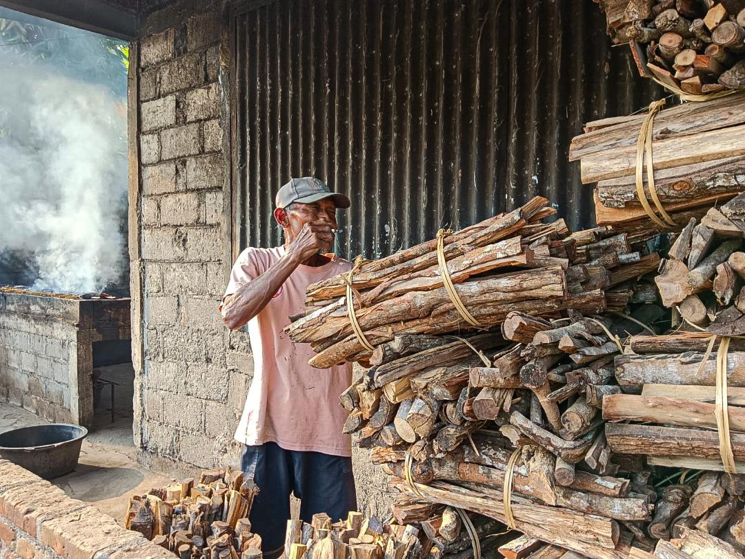 Pengumpul kayu bakar sedang menata kayu yang akan digunakan sebagai bahan bakar pembuatan mangut lele di Sewon, Bantul, Yogyakarta. | Foto: Media Asuransi/Arief Wahyudi