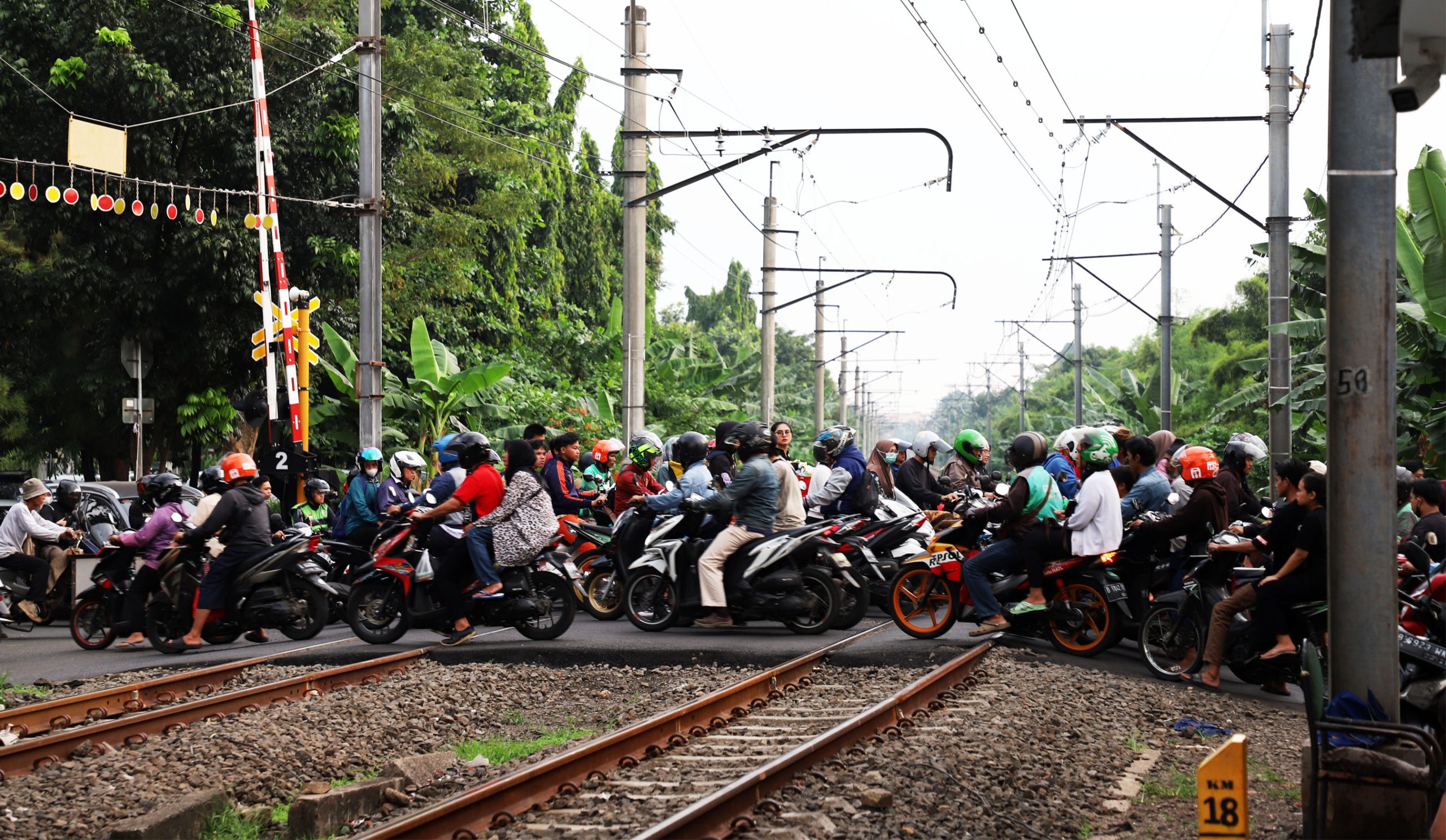 Sejumlah pengendara sepeda motor melintasi pintu rel Kereta Api (Commuter Line) di kawasan Bintaro, Tangerang  Selatan. Jalur kereta di kawasan Bintaro terbilang jalur sibuk kereta, terutama di jam-jam sibuk kerja. | Foto: Media Asuransi/Arief Wahyudi