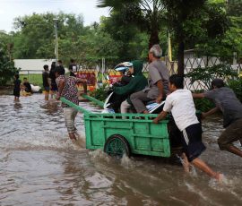 Warga pengguna sepeda motor yang terhadang banjir di Jalan Cileduk Raya, Sabtu, 6 Juli 2024), memanfaatkan jasa perahu gerobak untuk menyeberangi banjir. | Foto: Media Asuransi/Arief Wahyudi