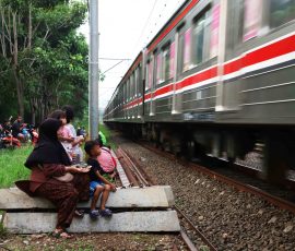 Warga, orang tua dan anak-anak berkumpul di pinggir jalur rel kereta listrik Bintaro menunggu kereta lewat. Meskipun memiliki risiko yang cukup tinggi, banyak orang tua yang kerap mengajak anaknya untuk datang ke lokasi tersebut saat sore hari sebagai sarana hiburan anak-anak mengisi waktu liburan sekolah. | Foto: Media Asuransi/Arief Wahyudi